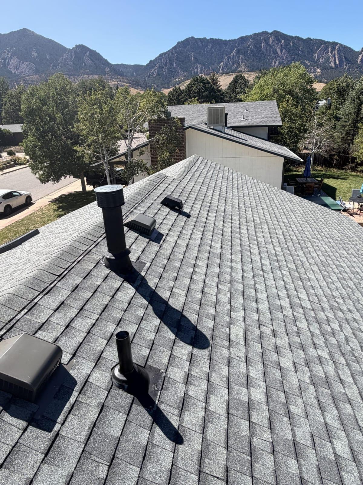 Completed SQ Roofing shingle roof in Boulder, Colorado, with the Flatirons rising behind it