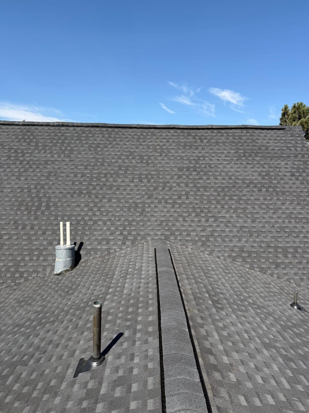 Charcoal architectural shingle roof with a continuous ridge vent and newly flashed plumbing vents
